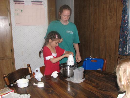 Katie and Andrea mix a cake.
