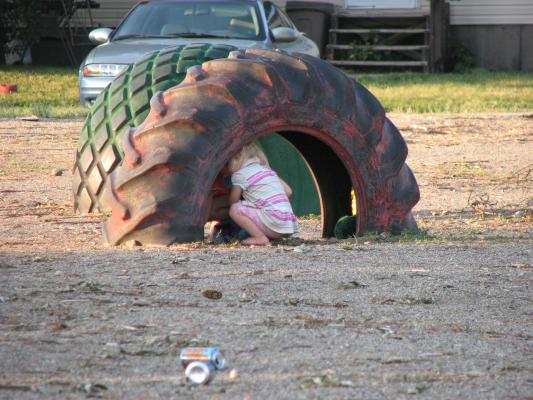 Sarah under a red tire at the park.