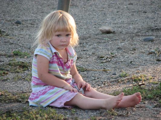Sarah sits on gravel at park.