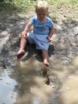 Noah plays in a mud puddle.