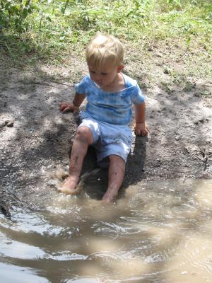 Noah plays in a mud puddle.