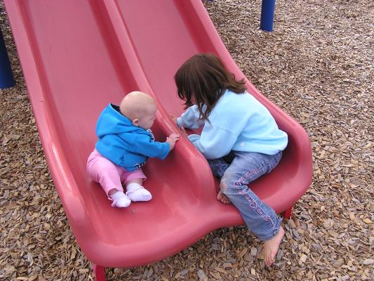 Andrea and Sarah on a slide at the playground.